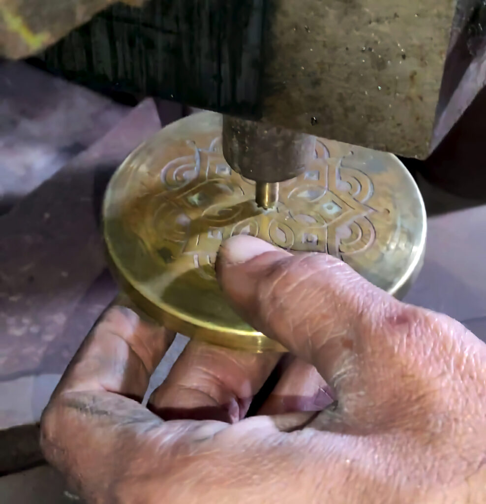 Artisian working on brass lid